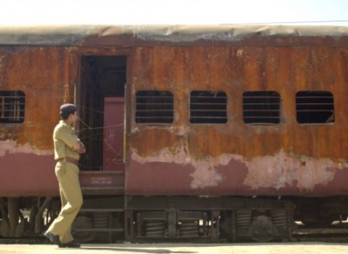A policeman walks past the burnt Subarmati Express train in February 2002.