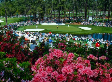 Golf fans watch practice on the par three 16th hole during a practice round of The Masters yesterday. Storms hit the Augusta area overnight.