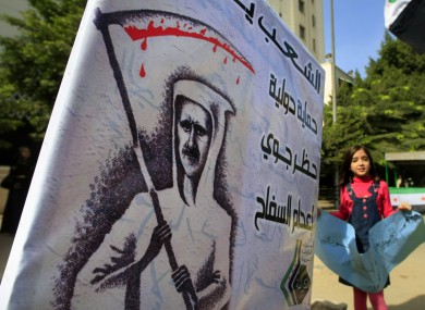 A Syrian girl flashes anti-Syrian regime slogans in front of an anti-Bashar poster outside the Arab League headquarters in Cairo, Egypt,