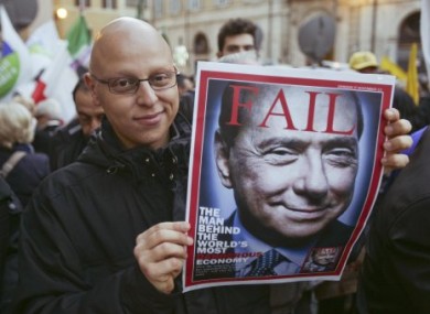 A man, waiting for the resignation of Berlusconi, shows a mock magazine cover displaying the former PM in Rome.