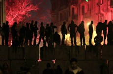 Egyptian protesters stand on a cement block barrier separating the interior ministry from Tahrir Square, Cairo last night.