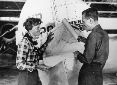 1937: Amelia Earhart and Fred Noonan pose with a map of the Pacific showing route of their last flight.