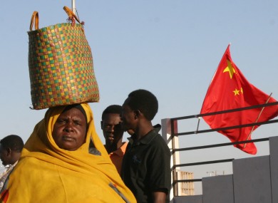 A Sudanese woman walks past a Chinese flag on a street in Khartoum