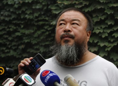 Dissident artist Ai Weiwei listens as his lawyer announces over a speakerphone the verdict of Ai's lawsuit against the Beijing tax authorities in Beijing Friday, July 20, 2012