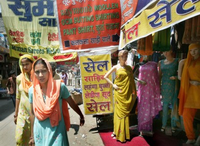 Women walk past a fabric shop at a market in Gurgaon, a suburb of New Delhi, India