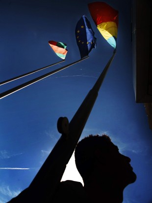 Bulgarian worker looks up at Bulgarian, Romanian and EU flags Sofia in 2006