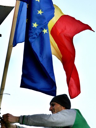 A Romanian man hoists EU and Romanian flags in Bucharest after Romania's entry to the EU in 2007.