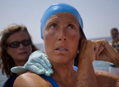 Diana Nyad preparing her hat for the swim as a team member helps apply a protective ointment on her skin.