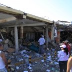 People stand in front of damaged commercial shops after a explosion in the Amuay refinery. (AP Photo/Ariana Cubillos/PA)