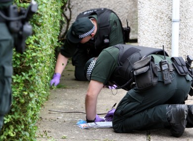 Police officers search a garden where drugs were found during a series of drug raids in the Lurgan area of Northern Ireland.