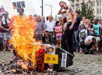 Demonstrators gather around a burning mock coffin with the pictures Marc Dutroux and Michelle Martin during a march to remember their victims, Brussels, August 2012.