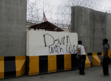 A Pakistani protester spray paints on the wall of the US consulate during a demonstration in Karachi, Pakistan, on Sunday