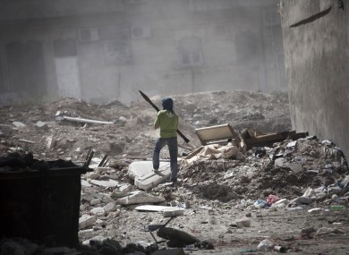 A Free Syrian Army fighter holds a rocket-propelled grenade launcher while taking cover after a tank blast in Aleppo, Syria.