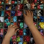 A Thai vendor arranges buttons at her stall while waiting for customers in Bangkok. (AP Photo/Sakchai Lalit)