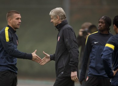 rsenal's Lukas Podolski, left, shakes hands with manager Arsene Wenger.