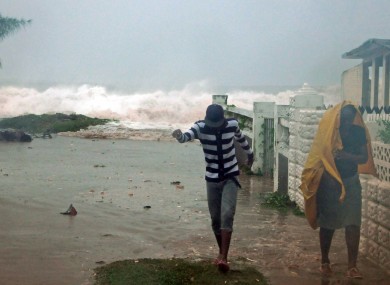 Residents evacuate their home as waves crash in the Caribbean Terrace neighborhood of eastern Kingston, Jamaica on Wednesday