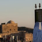 A Priest of the ancient Samaritan community, wrapped in a prayer shawl, holds up a Torah scroll during the pilgrimage for the holy day of the Tabernacles or Sukkot at the religion's holiest site on the top of Mount Gerizim near the West Bank town of Nablus. According to tradition, the Samaritans are descendants of Jews who were not deported when the Assyrians conquered Israel in the 8th century B.C. Of the small community of close to 700 people, half live in a village at Mount Gerizim, and the rest in the city of Holon near Tel Aviv. (AP Photo/Sebastian Scheiner)