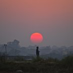 A Pakistani boy is silhouetted against sunset as he watches his friends playing cricket at a field on the outskirts of Islamabad, Pakistan. (AP Photo/Anjum Naveed)