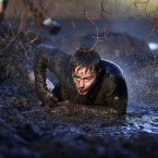 A competitor makes his way through Electroshock Therapy, fine wires which give you an electric shock, during the Tough Mudder event at the Cholmondeley Estate in Cholmondeley, Cheshire.