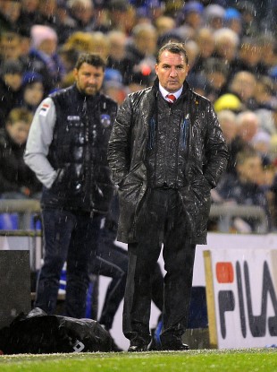 Liverpool manager Brendan Rodgers stands in the rain on the touchline.