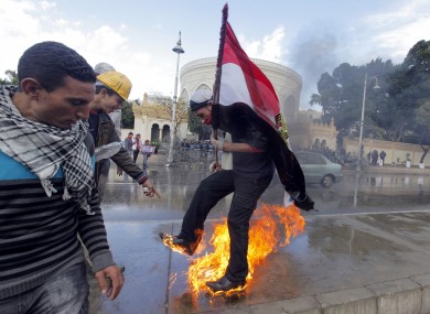 An Egyptian protester tries to escape from fire after he burned an anti-Mohammed Morsi banner in front of the presidential palace in Cairo.
